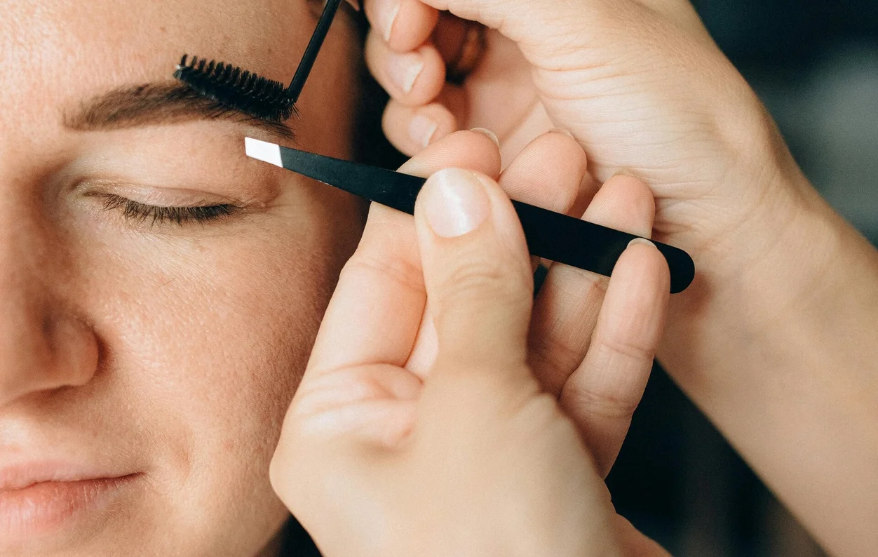 Mani della professionista con pinzette per extension sopracciglia